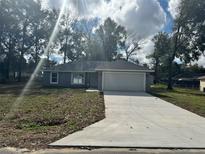 Charming one-story home with a fresh concrete driveway and attached two car garage at 3 Dogwood Trl, Ocala, FL 34472