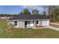 Charming single-story home featuring a gray exterior, attached garage, and well-manicured front yard at 15390 Sw 10 Pl, Ocala, FL 34481