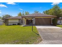 Single-story house with a brown garage door and stone accents at 21406 Sw Plantation St, Dunnellon, FL 34431