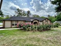 Charming single-story home with an arched entryway, manicured lawn, and vibrant pink flowering shrubs at 4215 Se 24Th Ter, Ocala, FL 34480