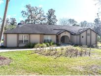 Lovely single-story home with an arched entryway, manicured lawn, and mature landscaping at 4215 Se 24Th Ter, Ocala, FL 34480