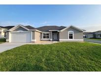 Charming single-story home featuring a well-manicured lawn, attached two-car garage, and neutral exterior paint at 5892 Sw 82Nd Ln, Ocala, FL 34476
