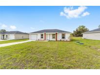 Charming single-story home with a well-manicured front lawn and a driveway leading to the garage at 14363 Sw 27 St, Ocala, FL 34481