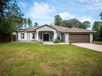 Charming single-story home featuring a two-car garage and a well-manicured front lawn at 12805 Sw 64Th Ln, Ocala, FL 34481