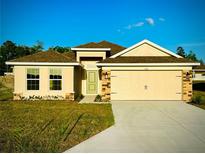 Charming one-story home with a two-car garage, a well-manicured lawn, and a beautiful pale yellow facade at 3127 Ne 45Th Ave, Ocala, FL 34470