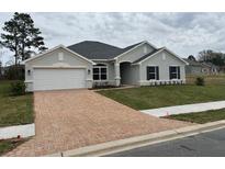 Charming one-story home with a brick driveway, lush green lawn, and a two-car garage at 7173 Sw 179Th Court Rd, Dunnellon, FL 34432