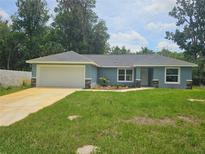 Charming single-story home with a lush green lawn and a two-car garage at 15067 Se 61St Ct, Summerfield, FL 34491