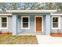 Inviting front porch featuring a modern exterior door, fresh paint, and well-manicured landscaping at 13212 Sw 113 Ln, Dunnellon, FL 34432