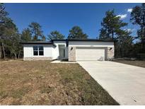 Charming single-story home with stone accents, a two-car garage and a well-manicured lawn at 14711 Sw 69Th Court Rd, Ocala, FL 34473