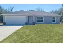 Charming single-story home featuring a well-manicured lawn, a two car garage, and a welcoming entrance at 22084 Sw Rainbow Lakes Blvd, Dunnellon, FL 34431