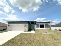 Charming single-story home featuring stone accents, a two-car garage, and a well-manicured lawn at 3015 Sw 132Nd St, Ocala, FL 34473