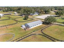 Aerial view of equestrian property with barn, riding arena, and paddocks at 10555 W Highway 40, Ocala, FL 34482