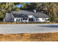 White ranch house with black trim, grey roof and riding arena at 10555 W Highway 40, Ocala, FL 34482