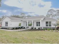 Beautiful single-story home with a white facade, covered porch, and lush landscaping at 5912 Ne 57Th N Loop, Silver Springs, FL 34488