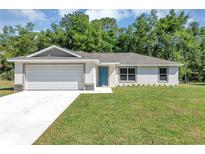 Charming single-story home with a well-manicured lawn, two-car garage, and a bright blue front door at 176 Pine Crse, Ocala, FL 34472