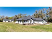 Beautiful single-story home with black trim, manicured lawn, and a matching guest house at 1725 W Hwy 329, Citra, FL 32113