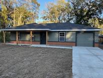 Newly constructed home with gray siding, brick accents, and a covered porch at 4131 Se 130Th Pl, Belleview, FL 34420