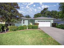 Charming single-story home featuring a well-manicured lawn, mature trees, and a two-car garage at 7947 Sw 83Rd Pl, Ocala, FL 34476