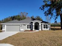 Charming single-story home featuring a well-manicured lawn, arched windows, and a gray color scheme at 7695 Sw 103Rd Loop, Ocala, FL 34476