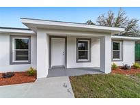 Charming home featuring a stylish front door, complemented by a well-maintained lawn and beautiful landscaping at 10177 Sw 137Th Ct, Dunnellon, FL 34432