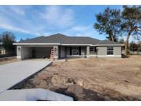 Newly constructed gray house with a two-car garage and a spacious front yard at 7613 Sw 103Rd Loop, Ocala, FL 34476