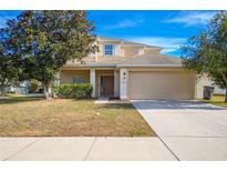 Two-story house with tan exterior, attached garage, and landscaping at 3921 Sw 51St Ter, Ocala, FL 34474