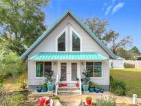 Charming home featuring a teal metal roof, unique windows, and a beautifully landscaped front yard at 26 Hemlock Cir, Ocala, FL 34472