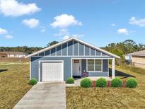 Newly built home with a gray exterior, white garage door, and landscaping at 3496 Sw 149Th Ct, Ocala, FL 34481