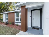 Charming single-story home featuring a white front door and modern wood-accented entry way with beautiful landscaping at 13573 Sw 115 Pl, Dunnellon, FL 34432