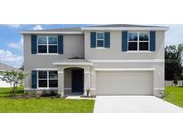 Two-story home featuring blue shutters, a manicured lawn, and a two-car garage at 9989 Se 161St Lane Rd, Summerfield, FL 34491