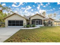 Single-story house with a screened porch, attached garage, and well-manicured lawn at 21 Fisher Trail Pass, Ocklawaha, FL 32179