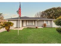 Charming single Gathering home featuring a lush lawn, attached garage, and welcoming front entrance at 7 Teak Loop Pl, Ocala, FL 34472