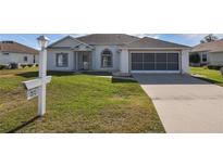 Single-story home with a two-car garage and landscaped lawn at 5520 Nw 26Th Ln, Ocala, FL 34482