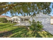 White single story home with attached garage and landscaped lawn at 2427 Due West Dr, The Villages, FL 32162