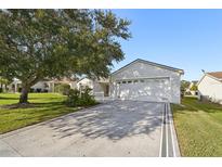 White house with attached garage and landscaped yard at 2427 Due West Dr, The Villages, FL 32162