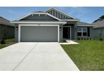Charming single-story home featuring a gray facade, two-car garage, and well-maintained landscaping at 4445 Sw 90Th Pl, Ocala, FL 34476