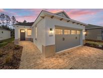 Craftsman style home with gray garage door and paver driveway at 10218 Sw 99Th Ln, Ocala, FL 34481