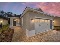 New home exterior with gray siding, white garage door, and brick walkway at 10282 Sw 99Th Ln, Ocala, FL 34481