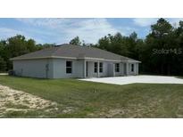 An exterior view showing the back of the house with a lawn and a concrete slab patio at 5489 Nw 12Th. St, Ocala, FL 34482