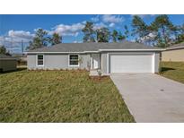 Newly constructed home with gray exterior, white garage door, and well-manicured lawn at 13351 Sw 83Rd Cir, Ocala, FL 34473