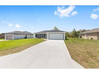 Charming single-story home featuring a gray and white exterior, a spacious driveway, and a well-manicured lawn at 4393 Sw 169 Lane Rd, Ocala, FL 34473