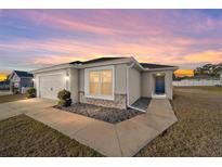 Charming one-story home featuring a two-car garage and beautifully landscaped front yard at sunset at 4955 Se 89Th Place Rd, Ocala, FL 34480