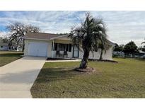 House exterior featuring a yellow single-story home with a palm tree and driveway at 10949 Sw 79Th Ter, Ocala, FL 34476