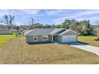 Newly constructed home with gray siding, gray roof, and a paved driveway at 963 Nw 65Th St, Ocala, FL 34475
