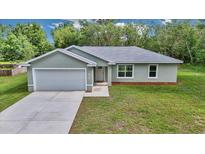 Charming single-story home featuring a light-gray exterior, attached garage, and well-maintained lawn at 963 Nw 65Th St, Ocala, FL 34475