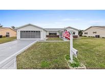 Beautiful single-story home with a two-car garage and a well-manicured lawn. American flag displayed at 9802 Se 178Th Ln, Summerfield, FL 34491