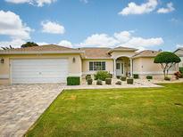 Charming one-story home featuring an attached two car garage and manicured lawn with lovely landscaping at 9910 Se 138Th Loop, Summerfield, FL 34491