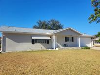 Tan single story home with attached garage, covered porch and a low retaining wall at 10736 Sw 62Nd Ave, Ocala, FL 34476