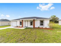 Charming one-story home featuring a clean white exterior, well-maintained lawn, and inviting front entrance at 15498 Sw 8 Pl, Ocala, FL 34481