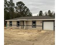 Newly constructed home with attached garage and sandy landscaping at 22564 Sw Rainbow Lakes Blvd, Dunnellon, FL 34431